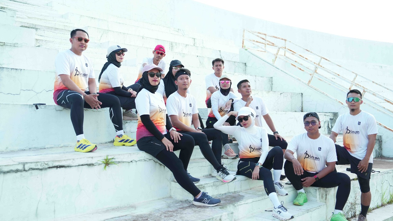 Sekelompok pelari dari Playon Brebes berfoto bersama dengan ceria di Alun-Alun Brebes setelah lari pagi, dengan latar belakang ikon kota.